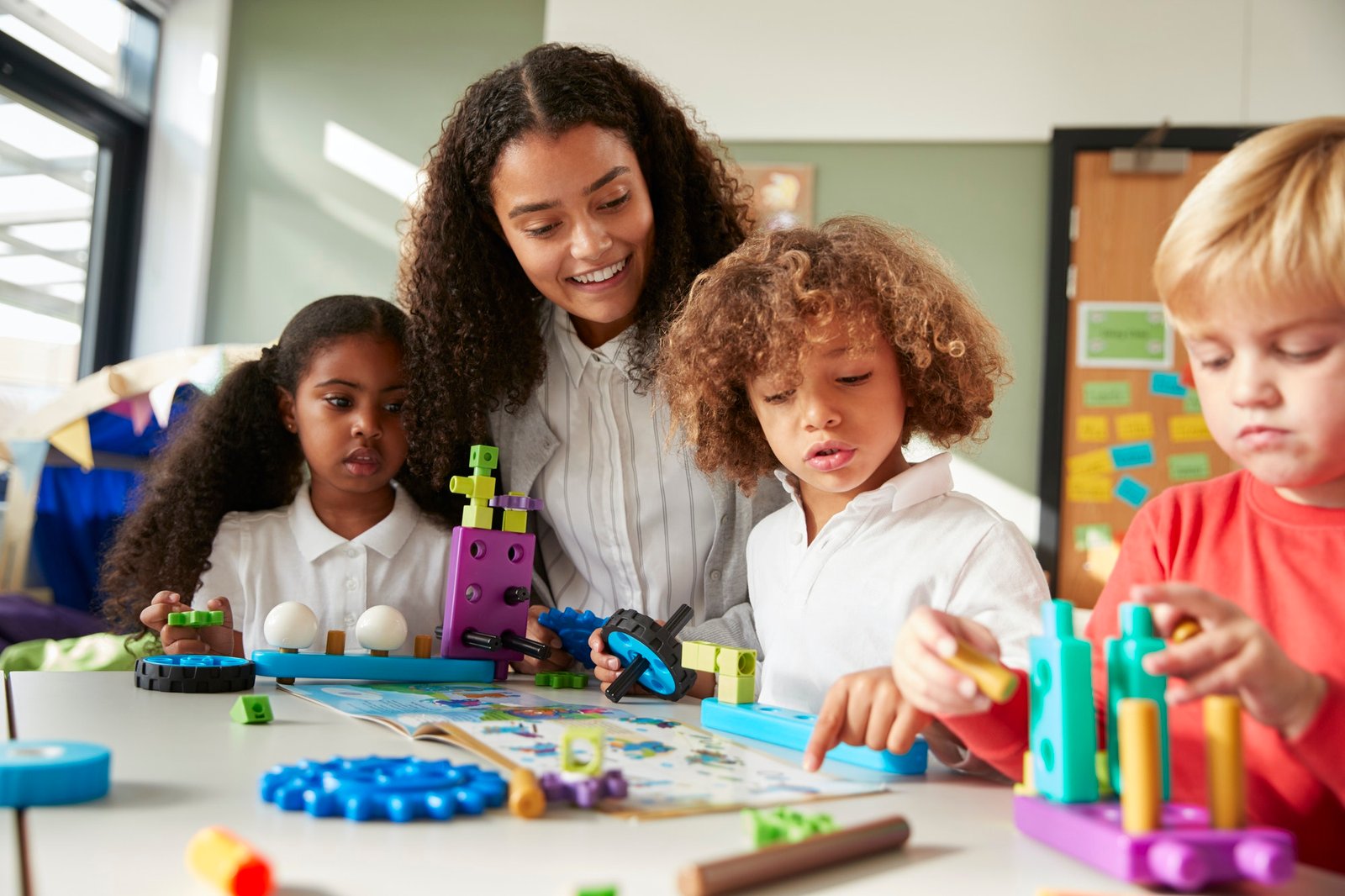 female-teacher-sitting-at-table-in-play-room-with-three-kindergartne-children-constructing.jpg female-teacher-sitting-at-table-in-play-room-with-three-kindergartne-children-constructing.jpg